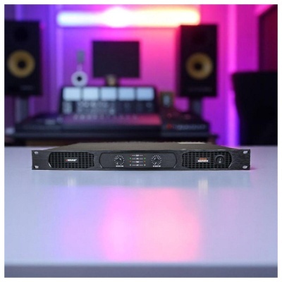 Amplificador de som preto numa mesa branca com luzes roxas e cor de rosa ao fundo