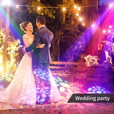 Casal a dançar em festa de casamento ao ar livre com luzes e projeções coloridas