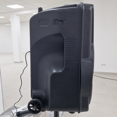 Coluna de som preta com rodízio em sala branca