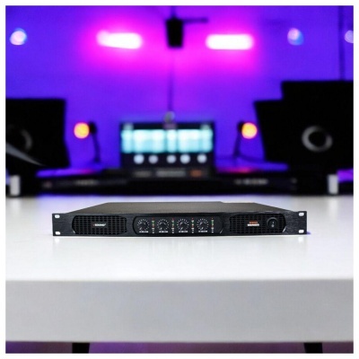 Amplificador de áudio preto com controlos frontais numa mesa branca em estúdio com luz roxa