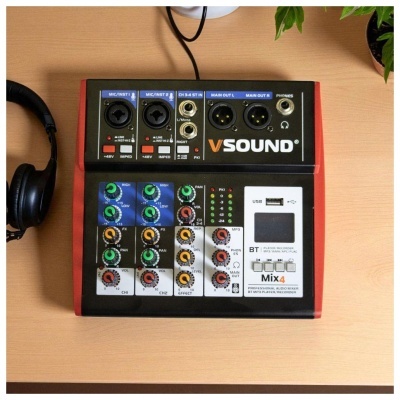 Mesa de mistura de áudio VSound Mix4 sobre mesa de madeira com auscultadores ao lado e plantas no fundo