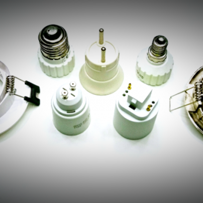 Adaptadores e suportes de lâmpadas brancos com detalhes metálicos sobre fundo branco e escuro