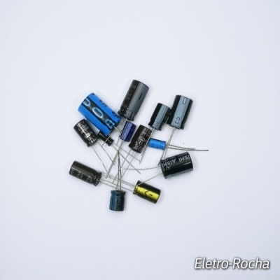 Conjunto de condensadores electrolíticos coloridos com pinos sobre fundo branco