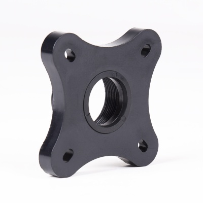 Peça metálica preta quadrada com furo roscado central e quatro furos nos cantos