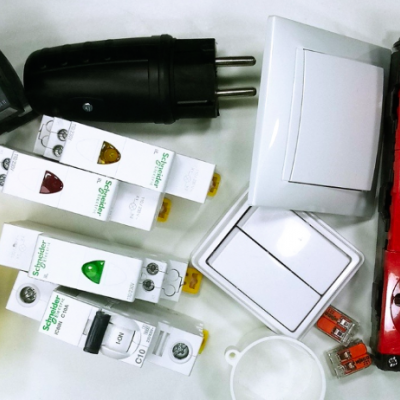 Componentes elétricos como interruptores, disjuntores, tomadas e conectores sobre superfície branca