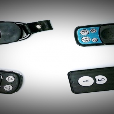 Quatro controles remotos pequenos com botões e chaves, em fundo branco.
