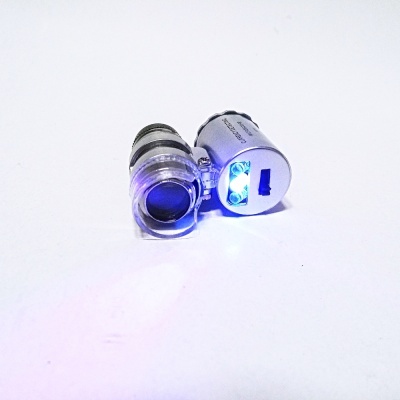 Duas pequenas lupas metálicas com luz LED azul sobre superfície branca