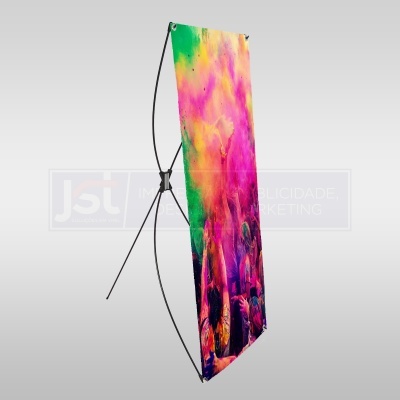 Banner publicitário colorido montado num tripé preto com imagem de pessoas e pó colorido