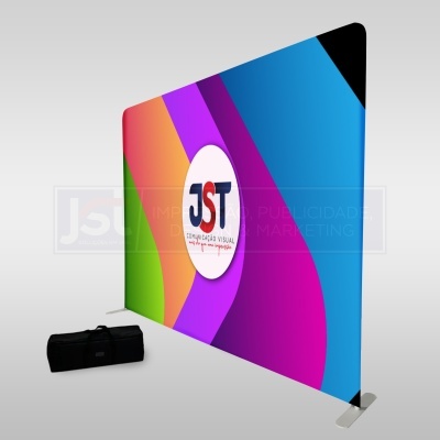 Painel publicitário portátil colorido com logo JST e mala preta para transporte.