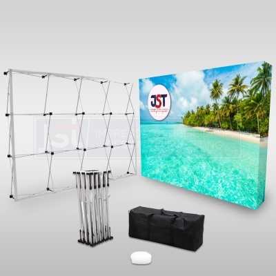 Expositor publicitário modular com imagem de praia e logótipo JST, estrutura metálica retrátil e acessórios de transporte.