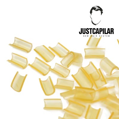 Pequenos cachos ou tubos castanhos claros translúcidos com texto JUSTCAPILAR NEW HAIR SYSTEM