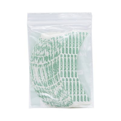 Máscara cirúrgica branca com texto verde LF MEDICAL embalada em saco zip transparente