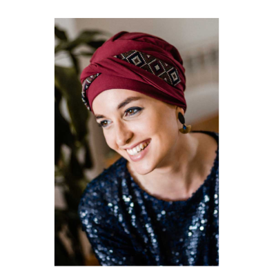 Mulher com gorro turbante vermelho com padrão geométrico e roupa azul brilhante