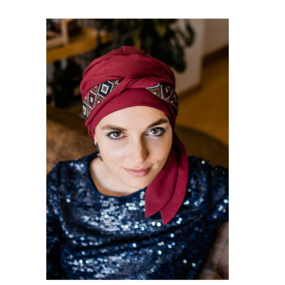 Mulher com turbante vermelho e camisa azul brilhante em ambiente interior