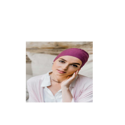 Mulher com lenço cor de vinho e roupa clara sentada num sofá com almofada bege