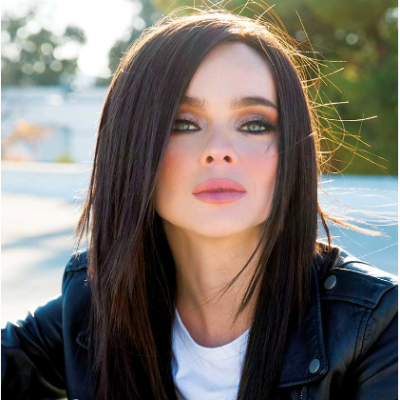 Mulher com casaco de cabedal preto e t-shirt branca ao ar livre, fundo desfocado