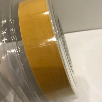 Rolo de fita adesiva amarela em embalagem plástica sobre fundo branco e cinza