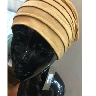 Touca tipo turbante amarela claro com pregas em manequim preto