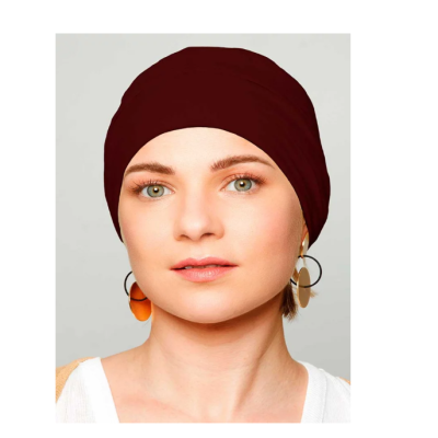 Mulher com gorro vermelho borgonha e brincos largos, fundo cinzento