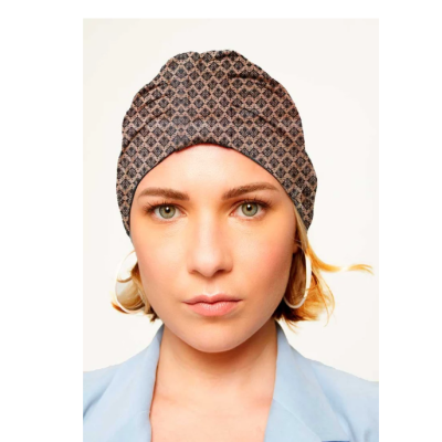 Gorro com padrão geométrico castanho e cinzento em mulher com brincos e blusa azul claro