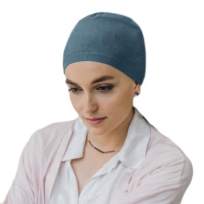 Mulher com gorro azul, camisa branca e casaco rosa claro em fundo branco
