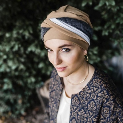 Mulher com turbante bege e casaco azul com padrão floral bege