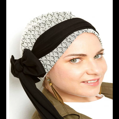 Lenço de cabeça branco e preto com faixa preta e laço, usado por mulher com casaco castanho claro