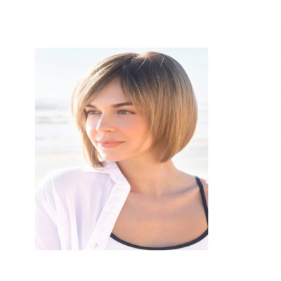 Mulher com cabelo castanho claro em corte bob usando camisa branca e camisola preta no exterior à beira-mar.