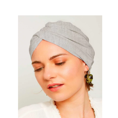 Mulher com turbante cinza claro e brinco pendente verde