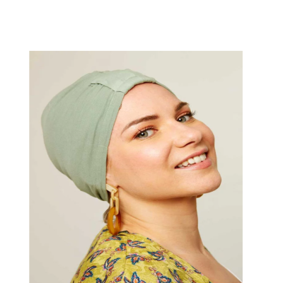 Mulher com lenço de cabeça verde claro, blusa amarela com padrão de borboletas e brincos grandes