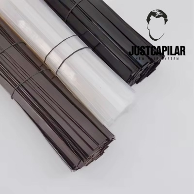 Três rolos de tecido plástico em preto, branco e castanho com logo JUSTCAPILAR