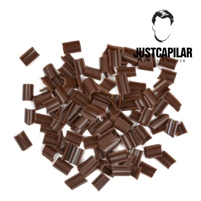 Partículas castanhas sobre fundo branco com logótipo JUSTCAPILAR