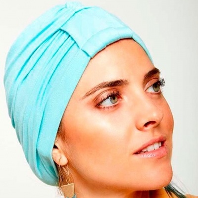 Pessoa com lenço azul claro tipo turbante e pendente dourado