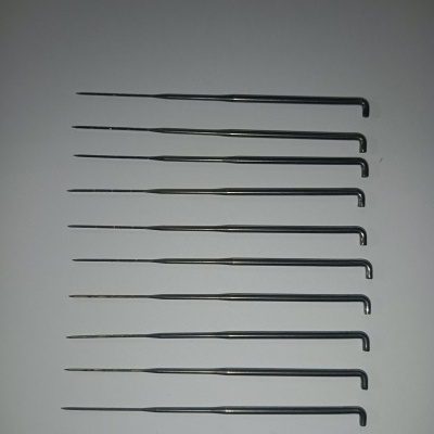 Oito agulhas metálicas finas com extremidades curvas alinhadas