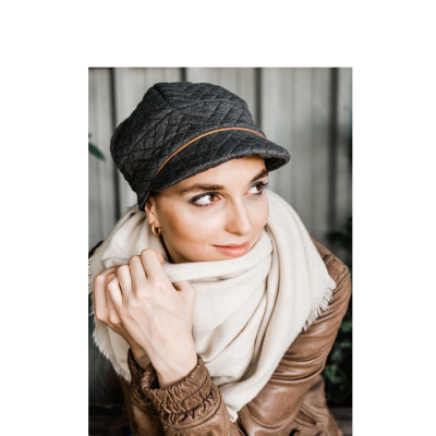 Mulher com chapéu preto acolchoado, cachecol creme e casaco castanho