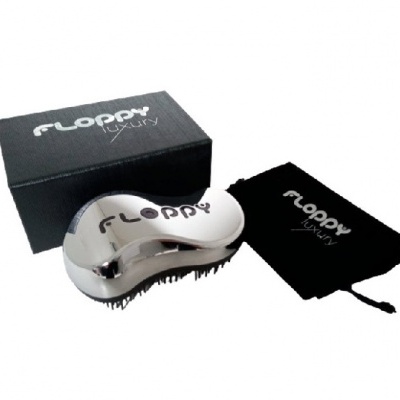 Escova de cabelo prateada com caixa e saco pretos com texto FLOPPY Luxury