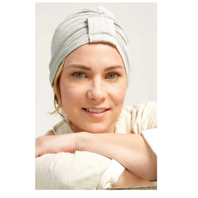 Mulher com faixa cinza claro na cabeça e roupa bege clara, fundo branco neutro.