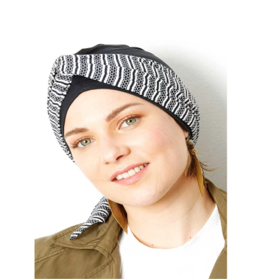 Turbante preto e branco com padrão geométrico em mulher com brincos castanhos.