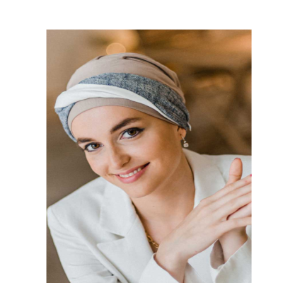 Mulher jovem com lenço cinza e bege na cabeça e blazer branco a sorrir