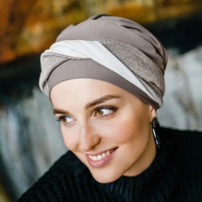 Turbante bege, castanho claro e branco com padrão torcido usado por mulher sorridente