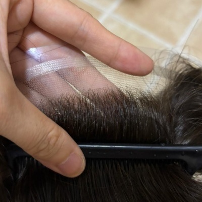 Mão a segurar tela transparente perto de cabelo castanho escuro penteado com pente preto