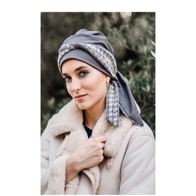 Mulher com lenço cinzento padrão e casaco creme com gola de pele