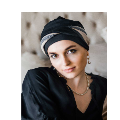 Mulher com turbante preto e colar de pérolas, fundo bege desfocado