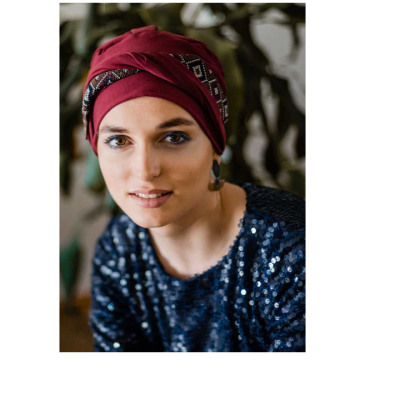 Mulher com turbante bordô e blusa azul de lantejoulas