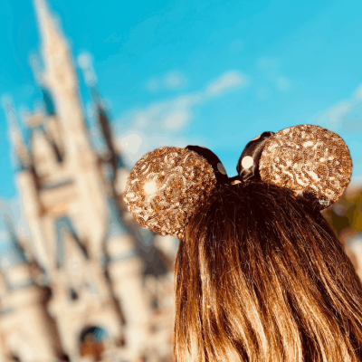 Faixa com orelhas douradas brilhantes em cabeça com cabelo castanho frente a castelo desfocado