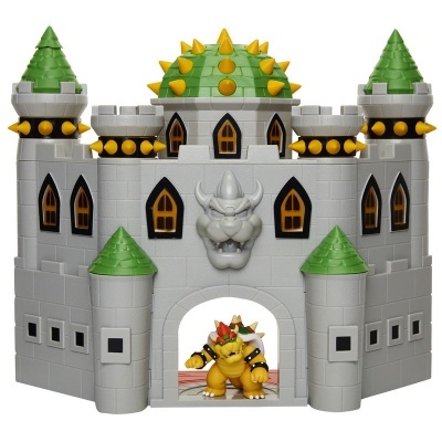 Castelo de brinquedo cinzento com torres verdes e figura amarela na entrada