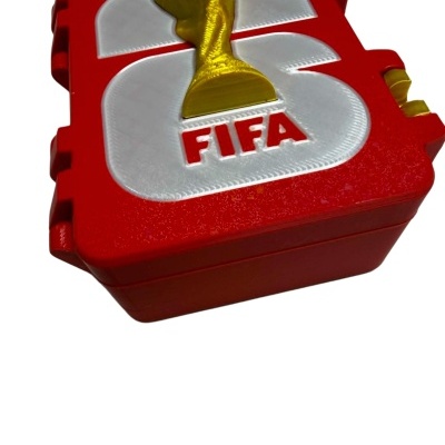 Caixa vermelha com tampa branca e figura dourada do troféu FIFA