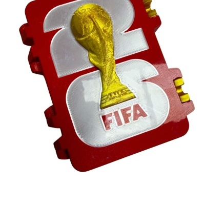 Bloco de espuma vermelho e branco com troféu da FIFA dourado e texto FIFA em relevo