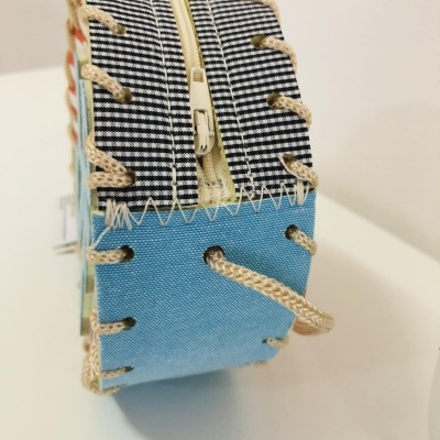 Mala pequena de tecido azul com padrão xadrez e fecho amarelo