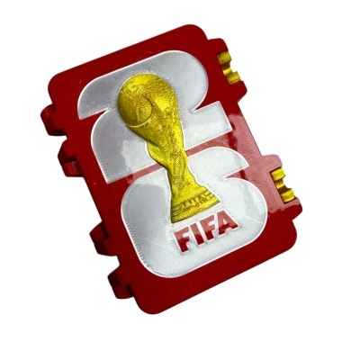 Relevo do troféu da Taça do Mundo FIFA em peça plástica vermelha e branca com texto FIFA